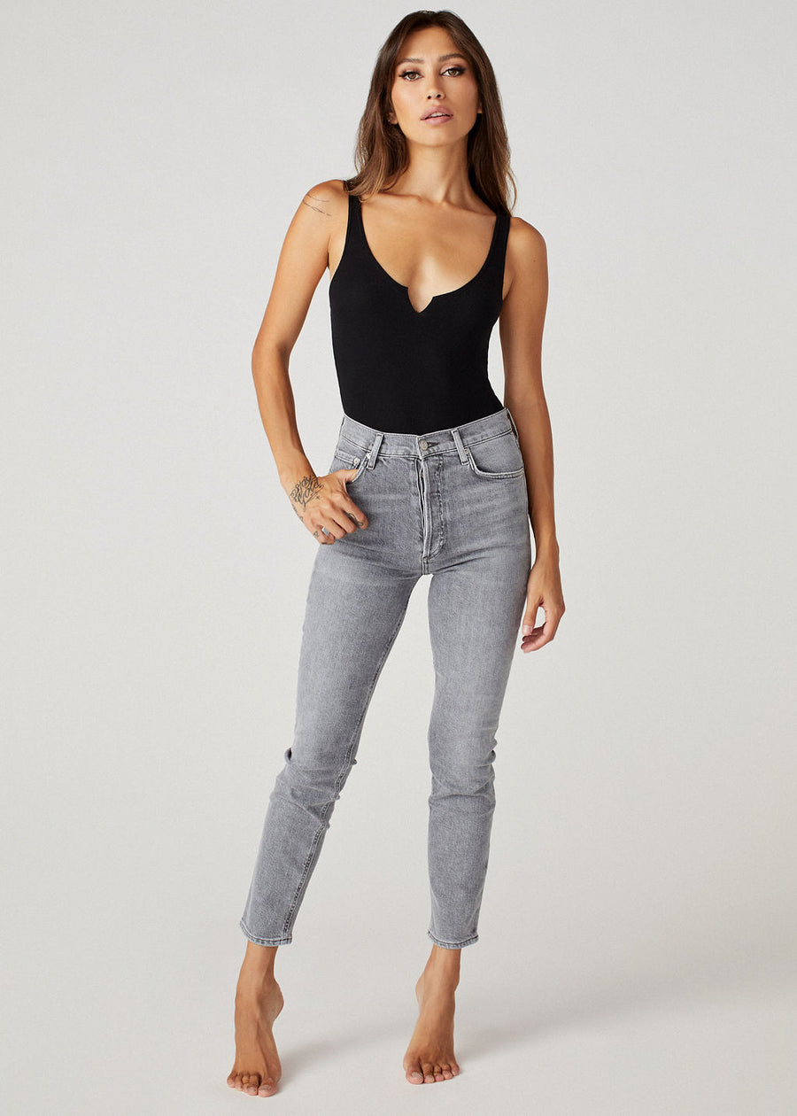 The model wearing the Brittaney V slit black bodysuit tank from Clyque and high waisted skinny jeans in light grey wash.