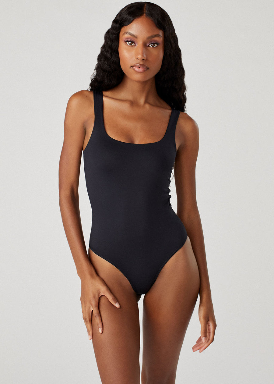 Model wearing the Sheera black bodysuit featuring a rounded square neck  and clean lines.