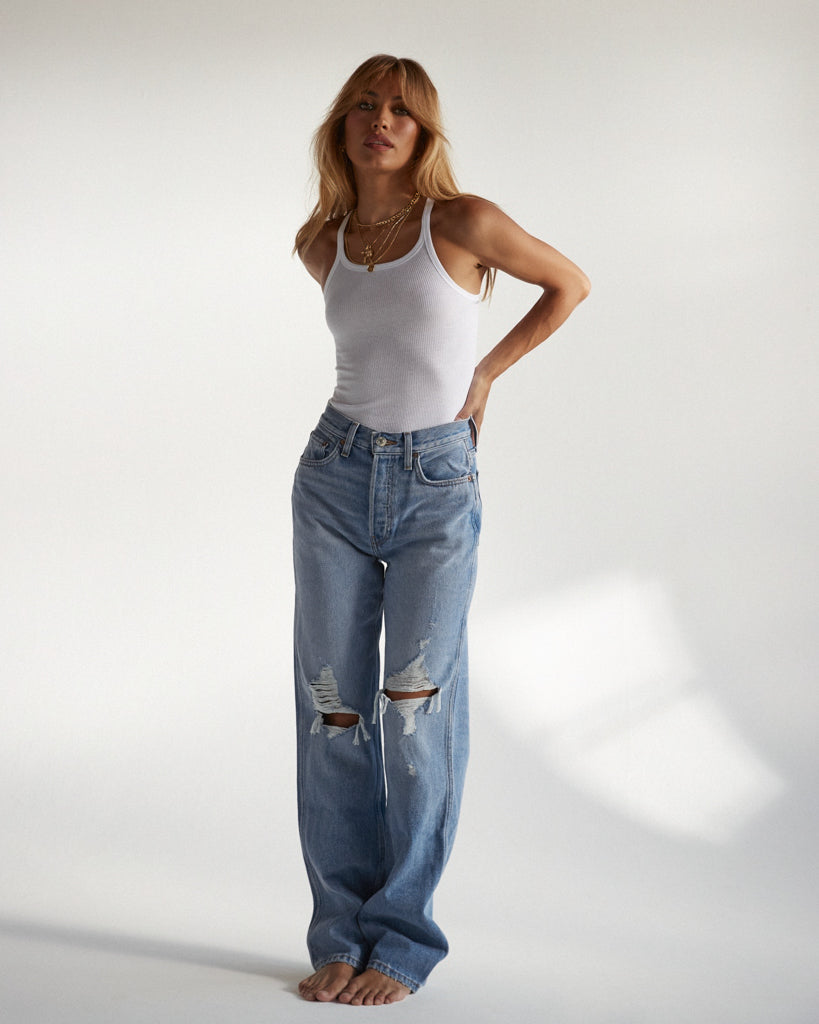 Blonde model wearing light blue ripped boyfriend jeans and the cotton West bodysuit in white from Clyque.