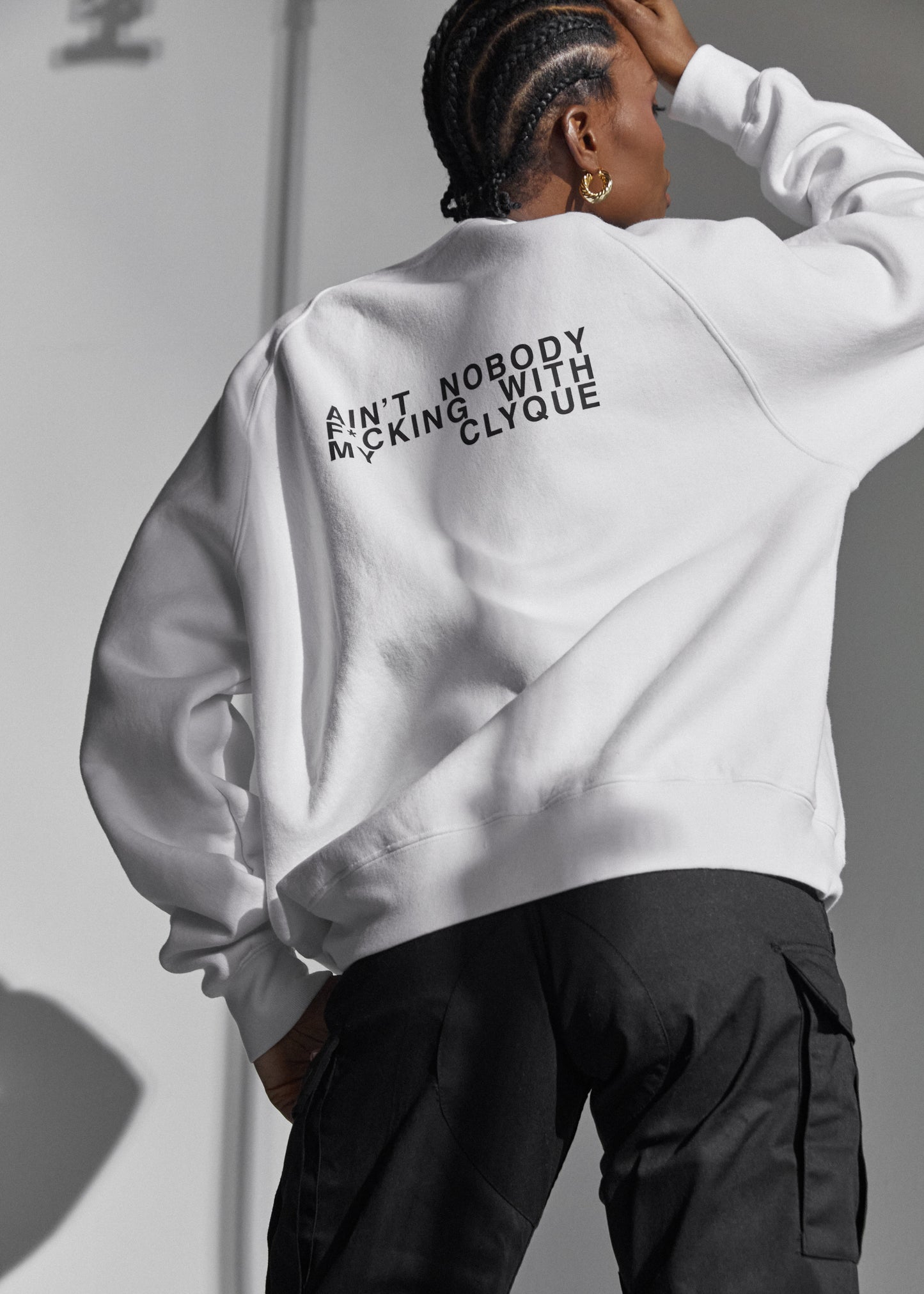 Model back facing the camera in an white unisex sweatshirt by Clyque showing the back  writing.