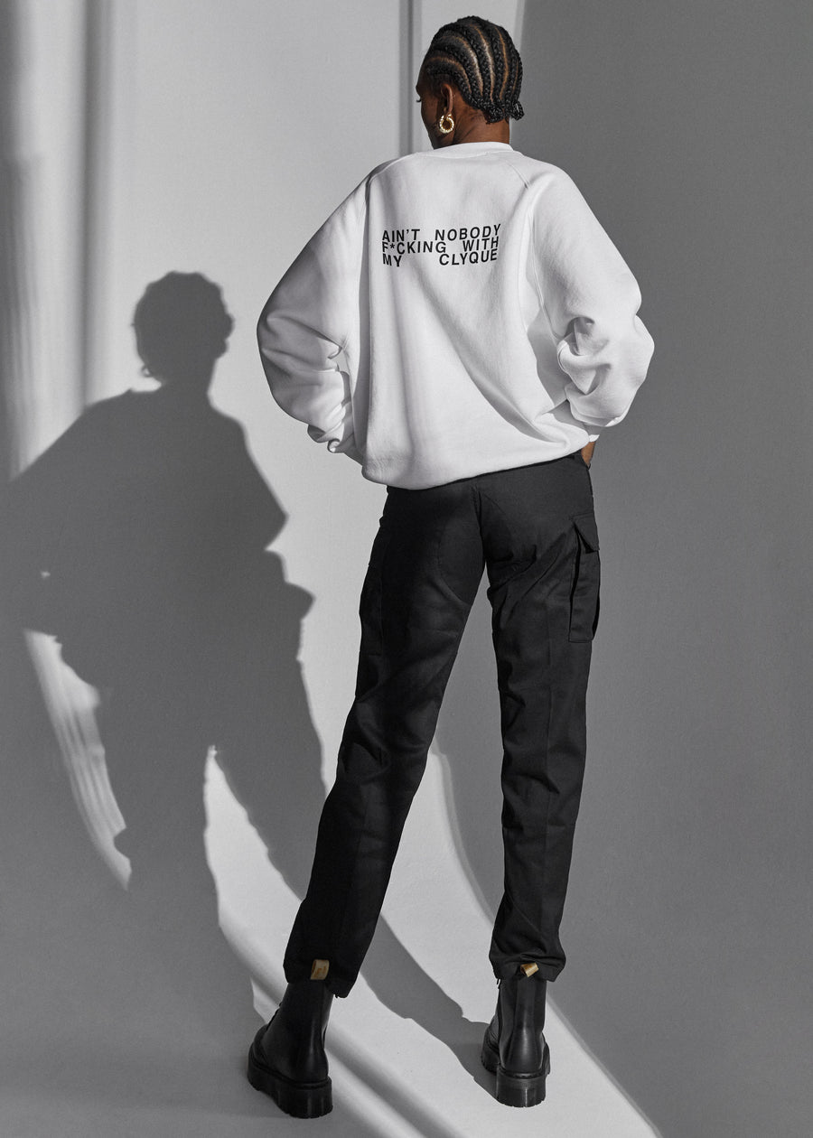 Model back facing the camera in an white over-sized sweatshirt, black pant and ankle boots. 